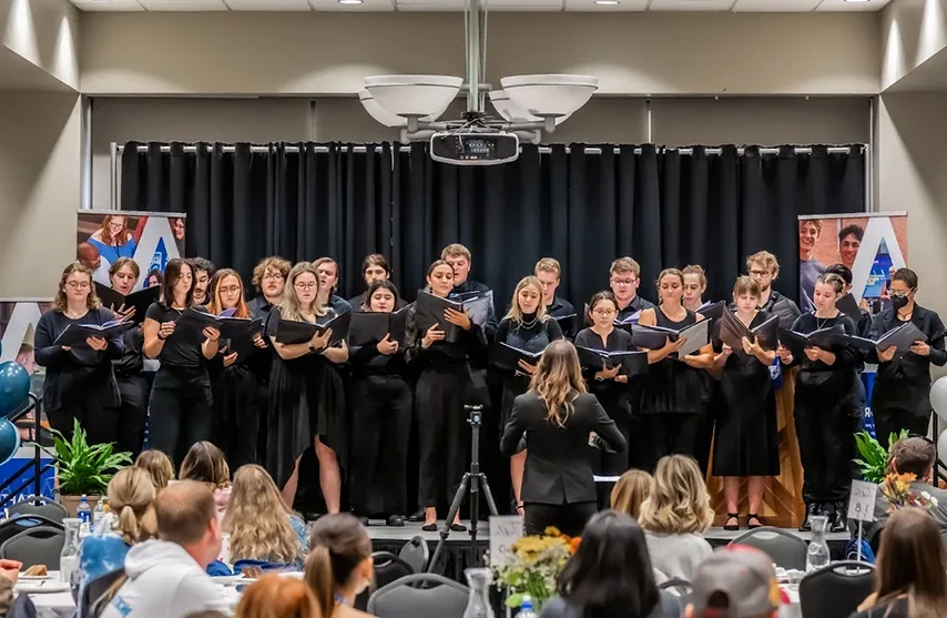 A student chorus performs for an audience.